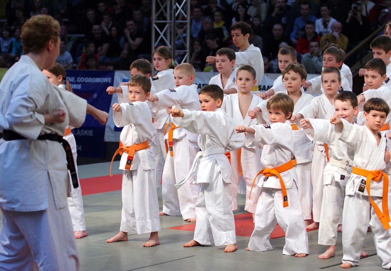 Dzieci ćwiczące techniki karate wspólnie z instruktorem